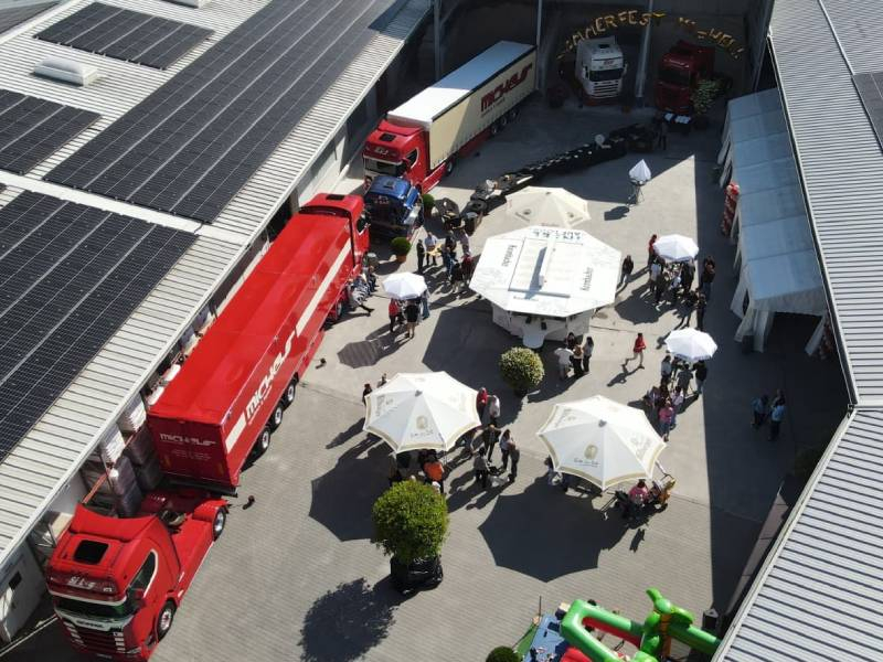 Zwei rote Lkw, Menschen und Sonnenschirme.